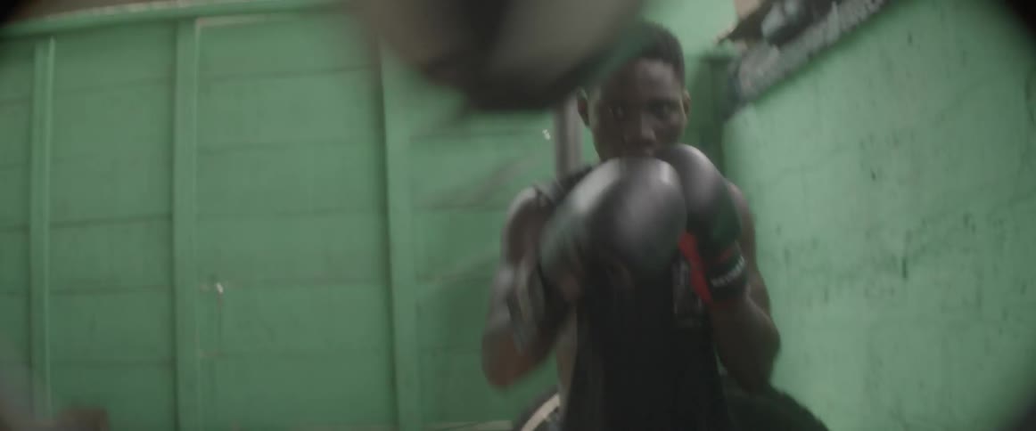 A man with boxing gloves punches a speed bag