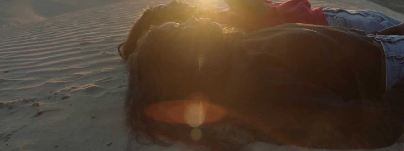 Two women lay in the desert at sunset