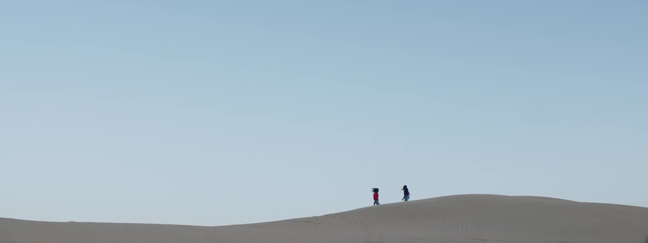 Two women running around on some sand dunes