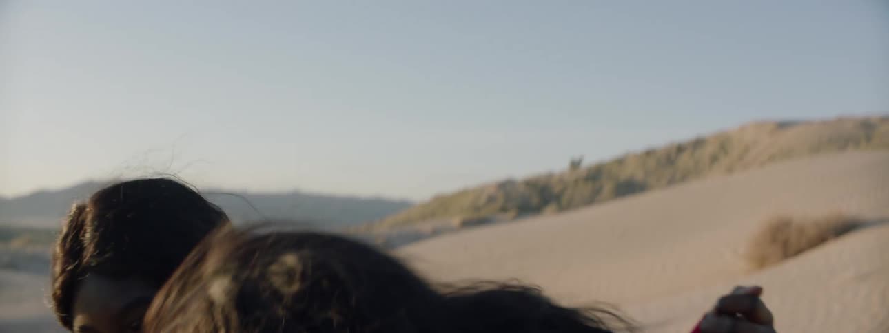 Two woman look into the distance and laugh as they hold each other
