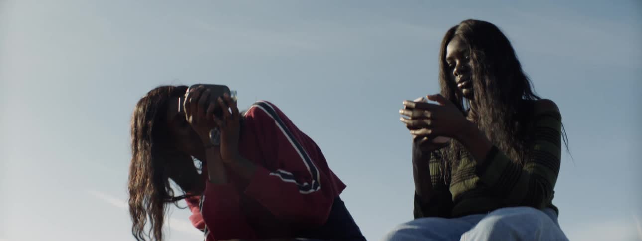 A woman films another woman with a camera as the other woman takes selfies