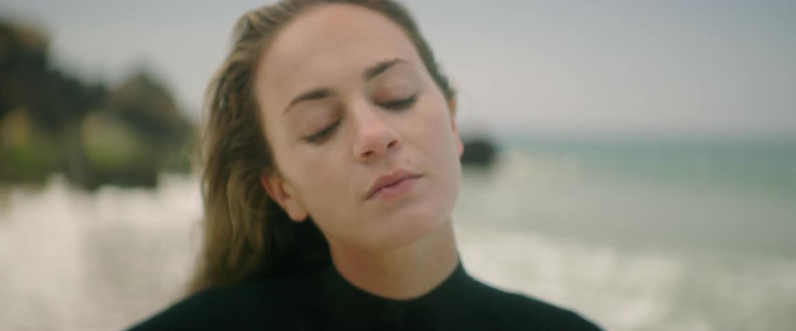 A woman in a wet suit stretches her neck and looks behind her