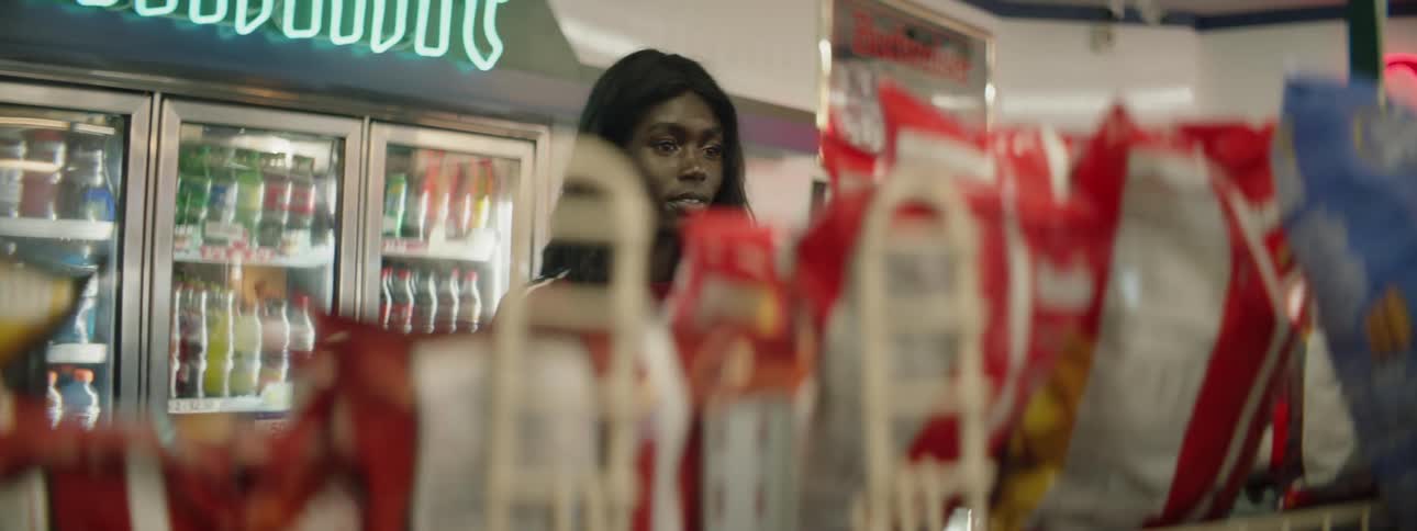 A woman grabs a bag of chips and walks through a store