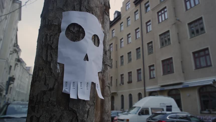 A piece of paper shaped like a skull stapled to a telephone pole