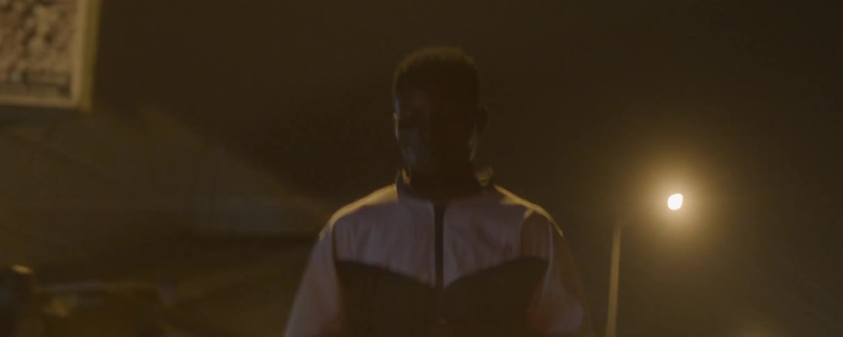 A man in a tracksuit running down a street at night