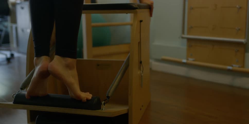 A woman stands on a springboard and then pushes it down all the way