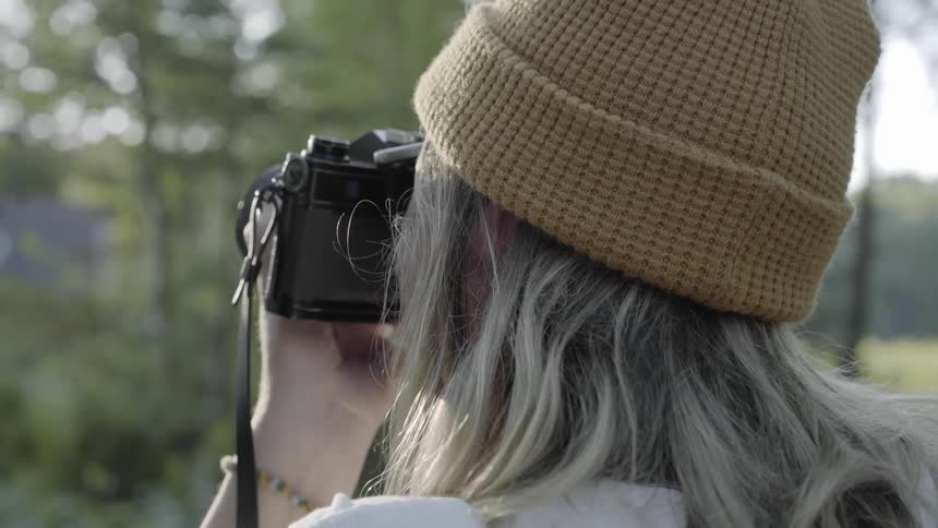 Person in beanie photographs forest