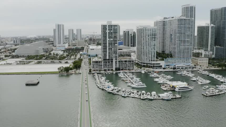 An aerial view of a city skyline that is near a bay with boats, buildings, and highways