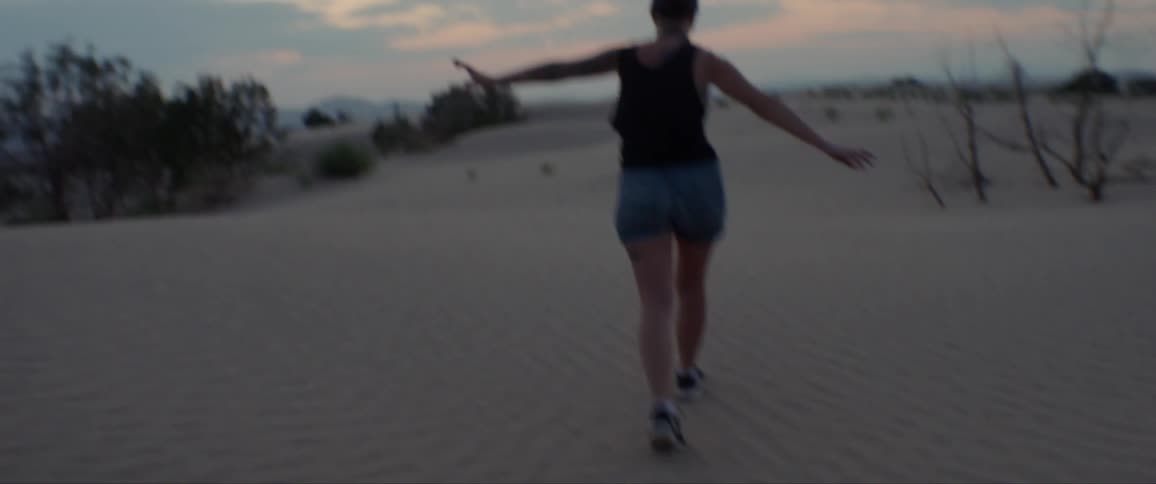 A woman walks a straight line in a desert