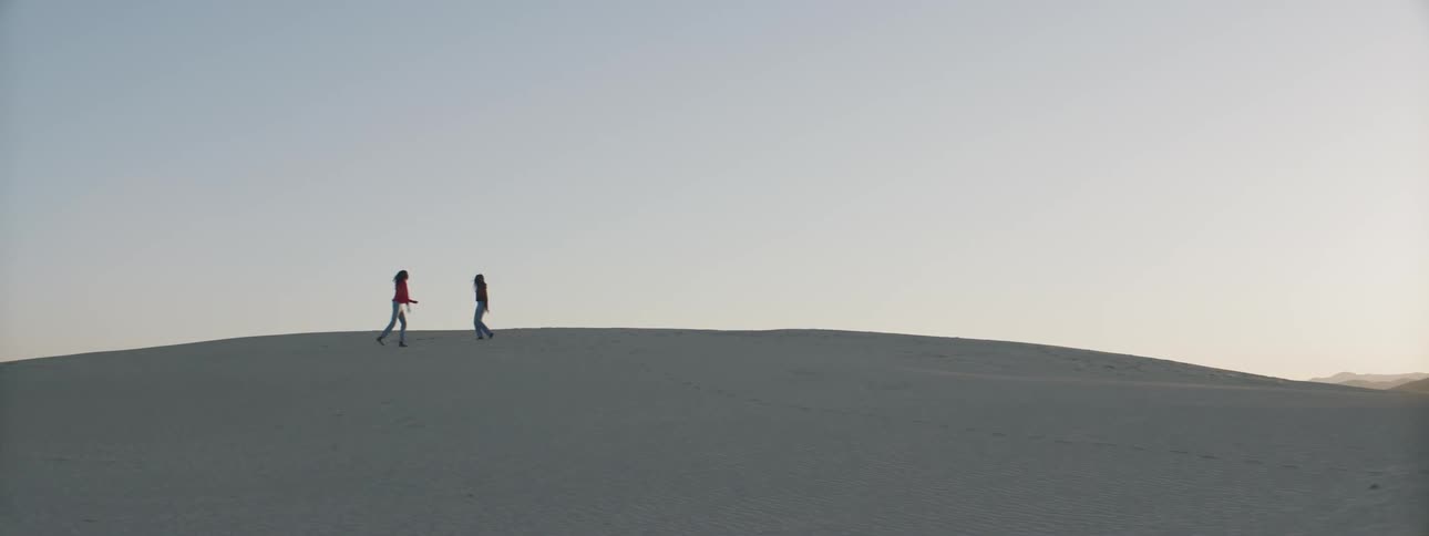 Two women dance and play in a desert