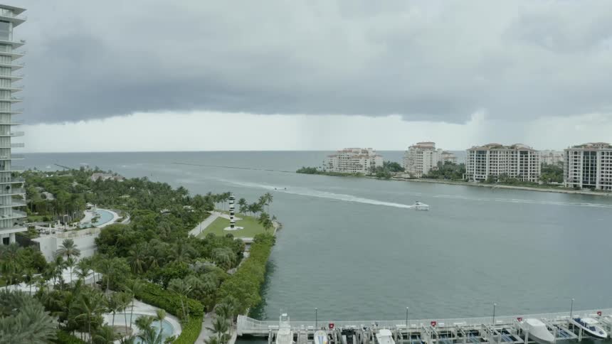 A boat drives in the ocean next to a city