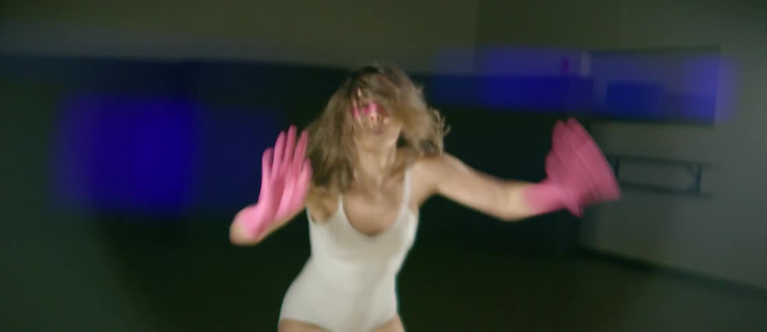 A woman with her hands painted pink is dancing inside in daylight
