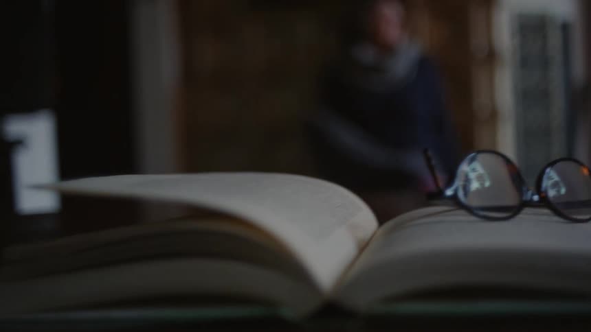 A pair of glasses lays on a book