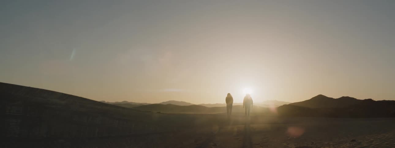 To people walk away towards the sunset