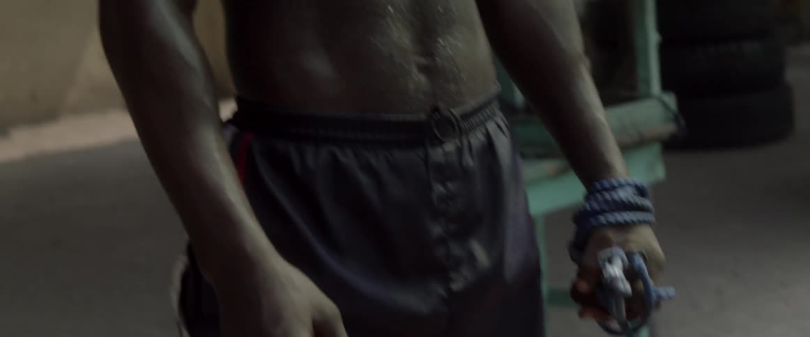 A man drenched in sweat coils a rope around his fist