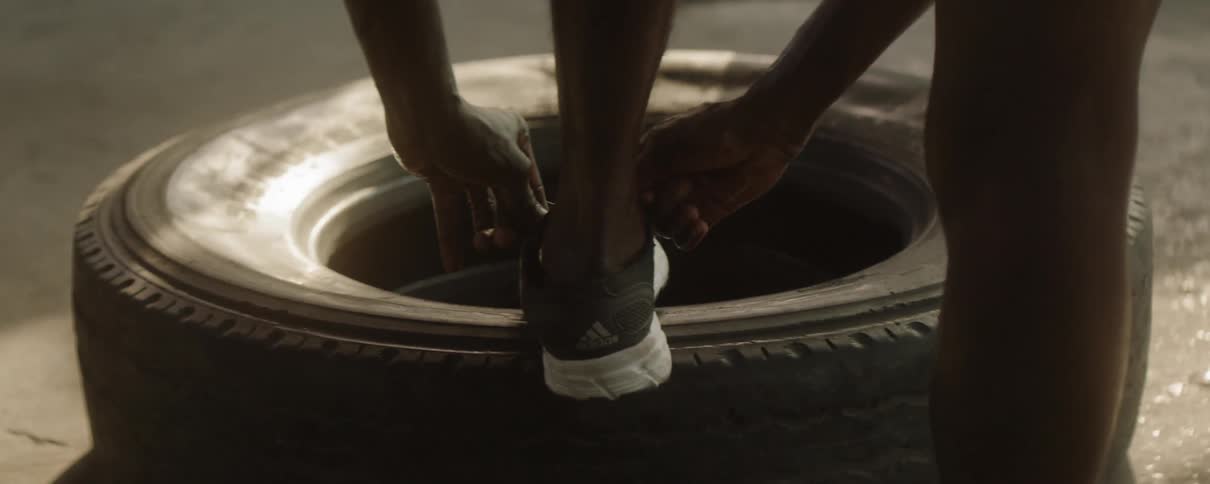 A man ties his shoe to exercise with a tire