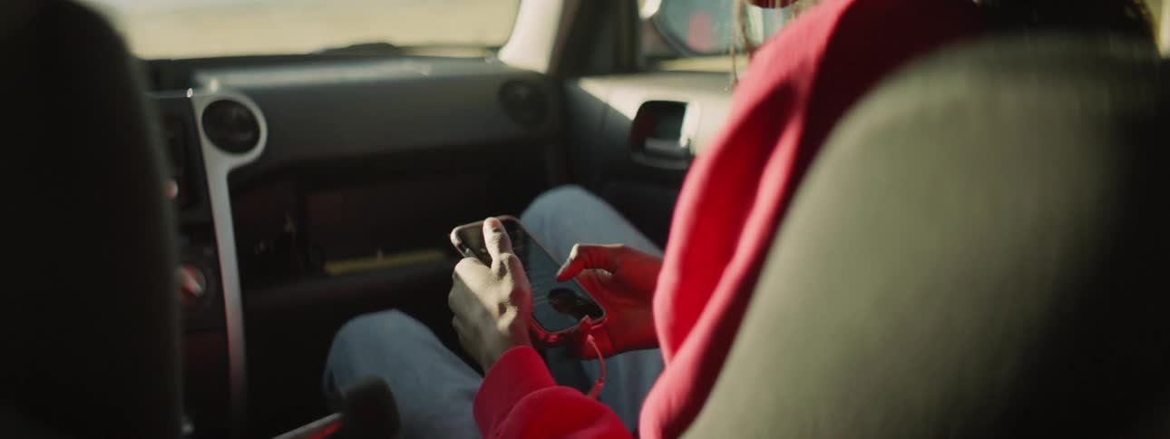 A passenger in a vehicle scrolling through their phone
