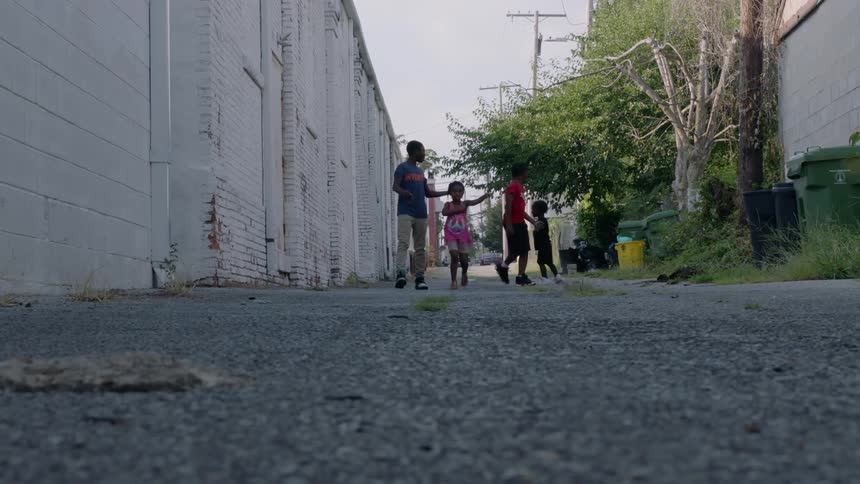 A group of four children walk down a city alley