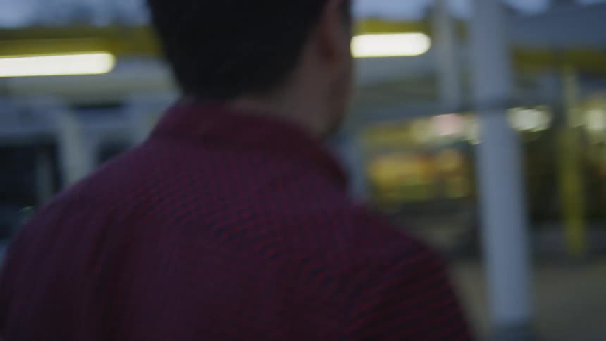 A man in a red and blue patterned shirt walks forwards and stops to turn around at the end