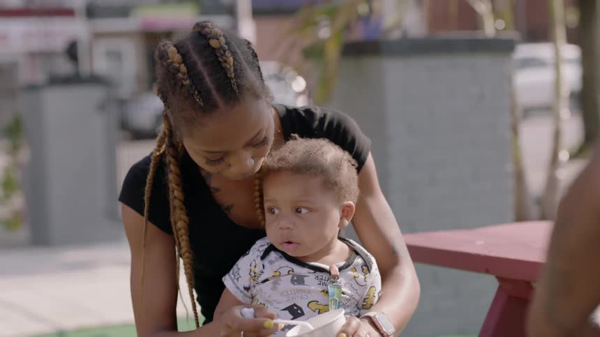 Woman scoops food out of a cup and feeds it to a child