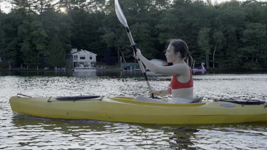 Woman paddles in a kayak down a river