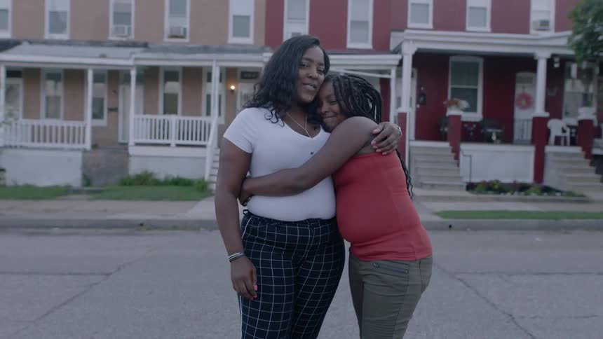 Two women hugging each other out on a street