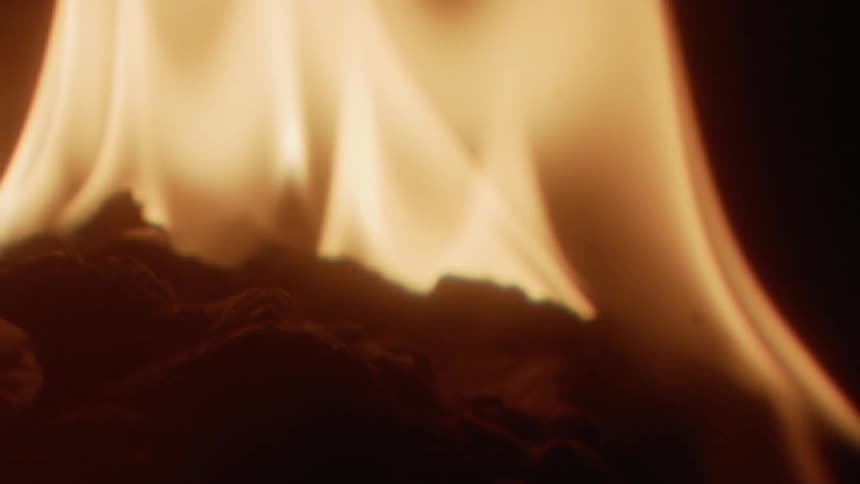 A fire burns brightly in the darkness