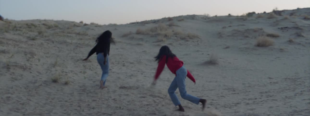 Two women run outside holding hands and hugging