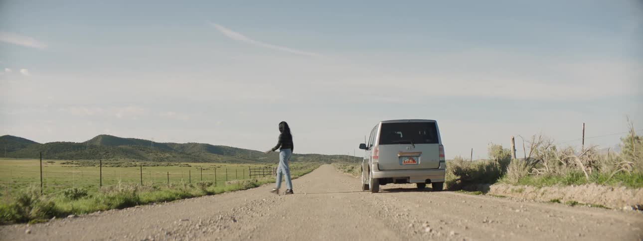 A woman gets out of a car and walks outside