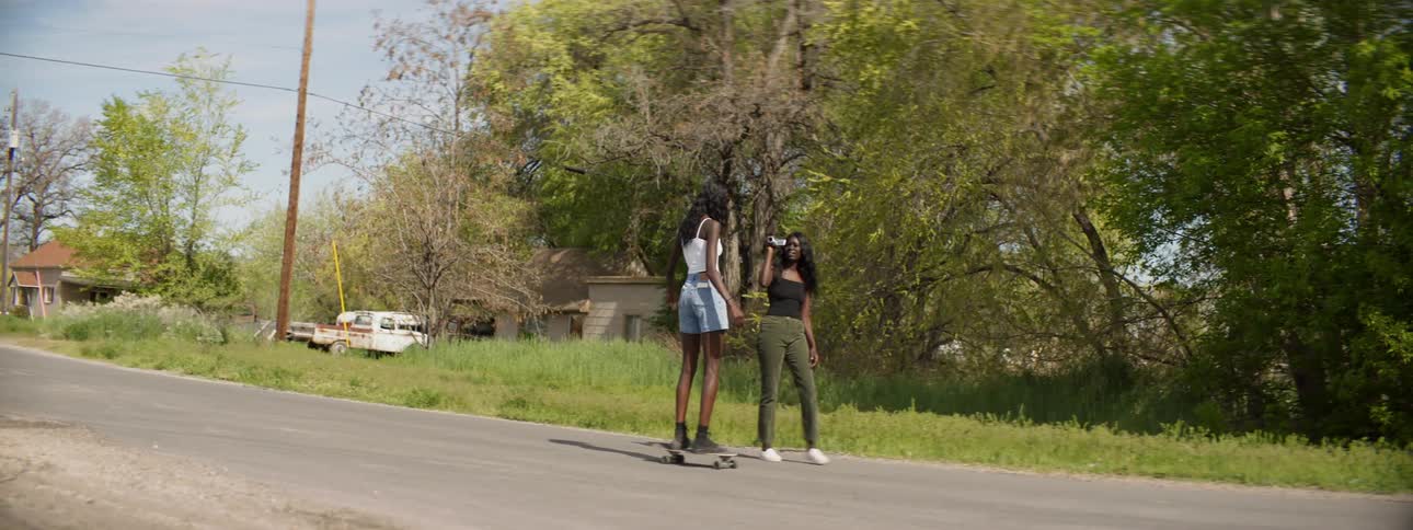 A woman records a video of her friend as the friend tries to skateboard