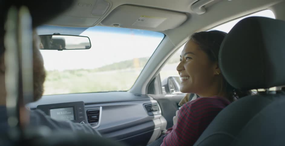 A woman smiling and laughing while sitting in the passenger seat of a car