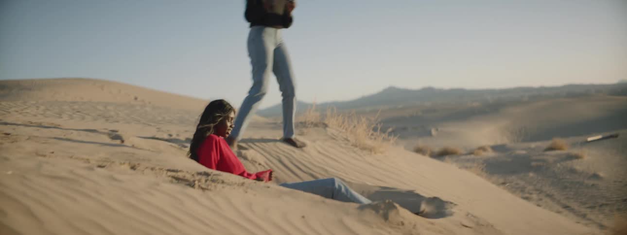 A woman sits down in a hole in the sand