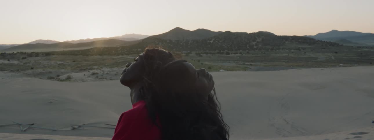 Two women standing back to back in the dunes in a desert