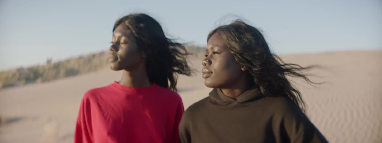 Two women standing out in the sand dunes next to each other
