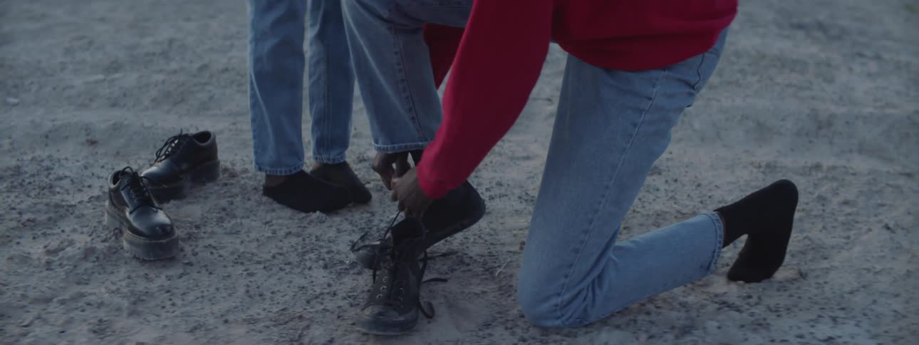Woman kneels down to lace up boots in the desert