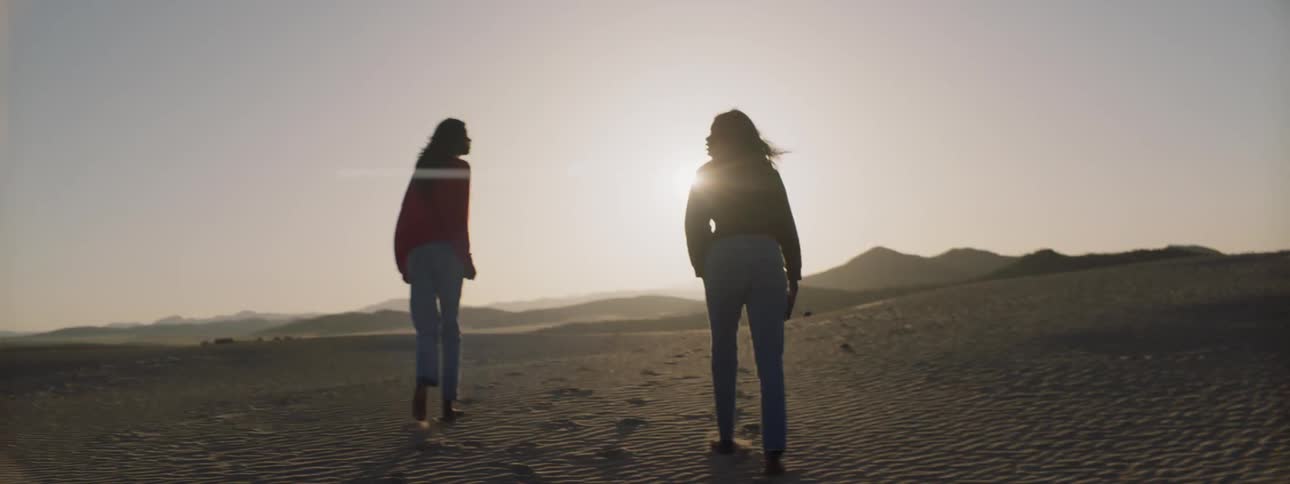 Two women walk in the desert on a sunny day