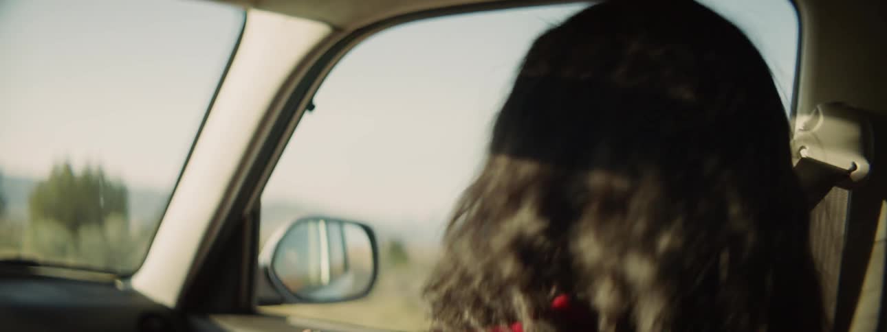 A woman dancing and singing in a passenger's seat of a car