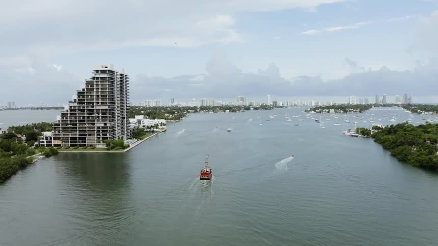 Boat sails down the river next to a large city