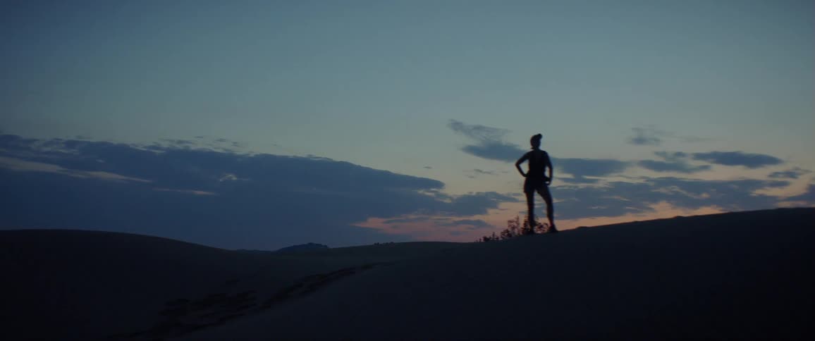 A woman stands with her hands on hill in the desert with her hands on her hips