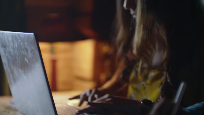 A woman types on a laptop while someone sits beside her