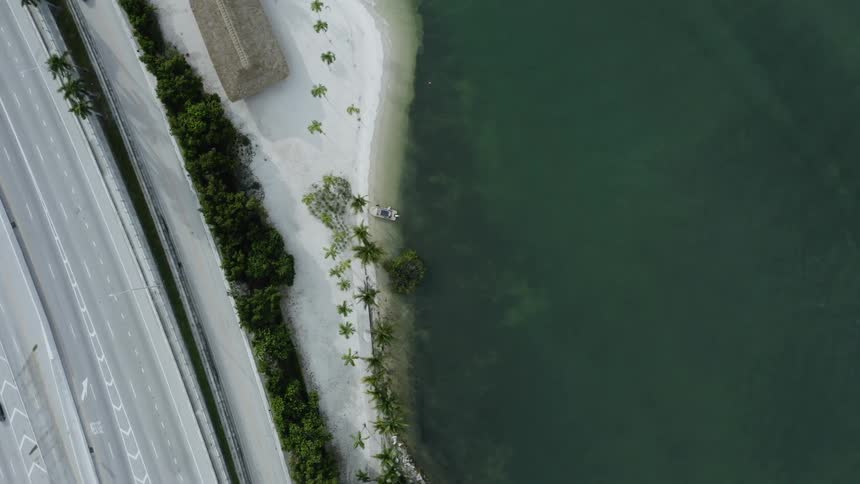Cars driving on a freeway next to a beach on the ocean