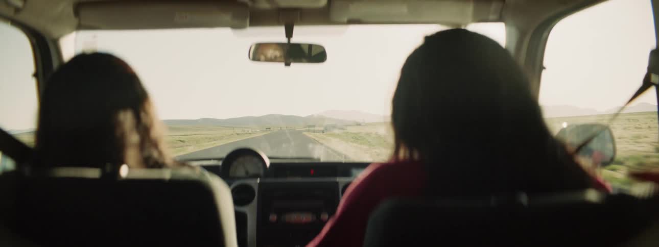 Two women ride down a highway in a car