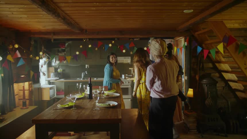 Group of women and a small child stand in a kitchen talking