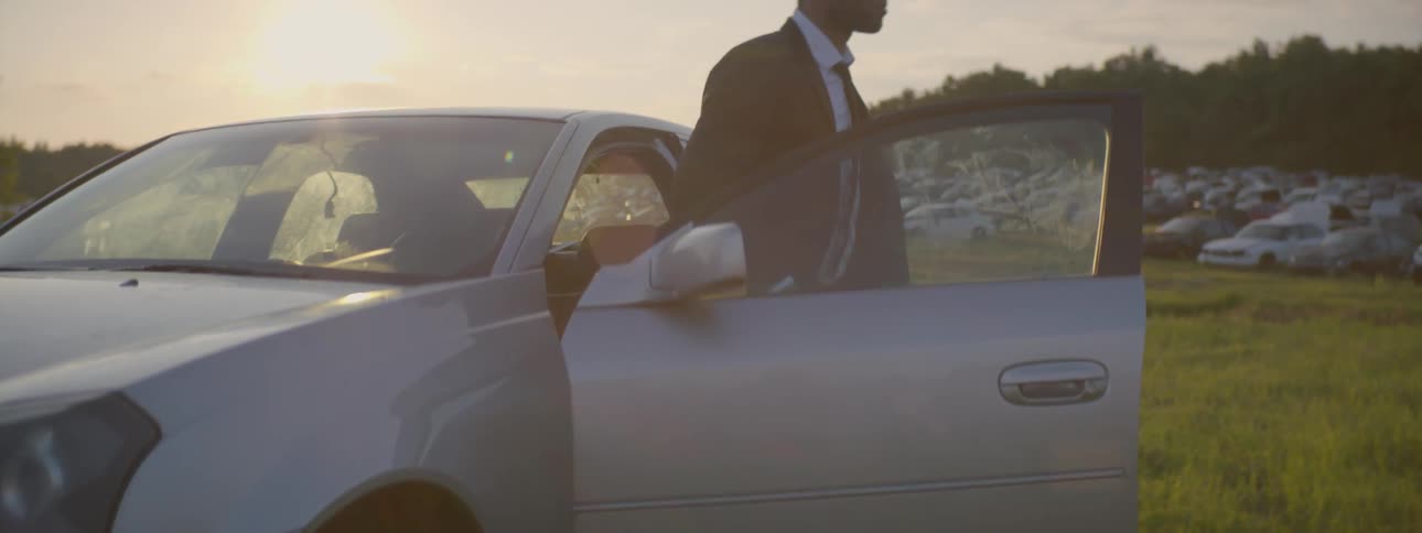 A man gets out of a car that's sitting in the sun