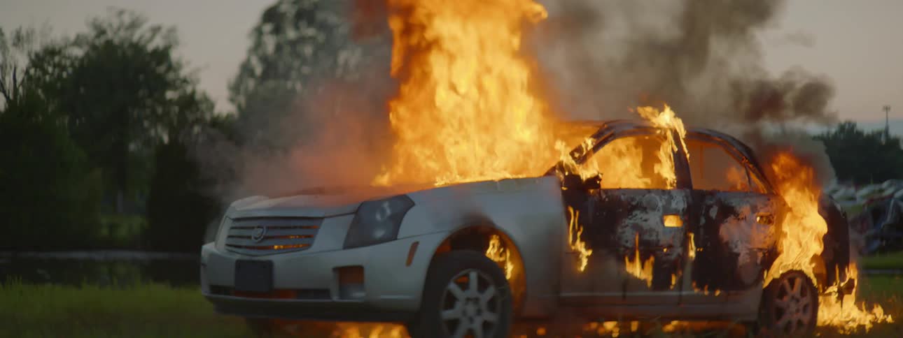 A car billows smoke as it burns violently