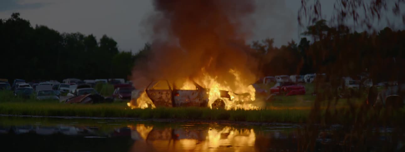 A car burns rapidly on the other side of a river