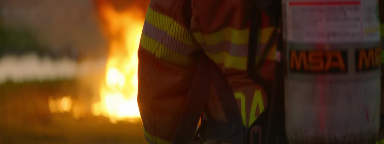 Fireman in fire suit approaches fire