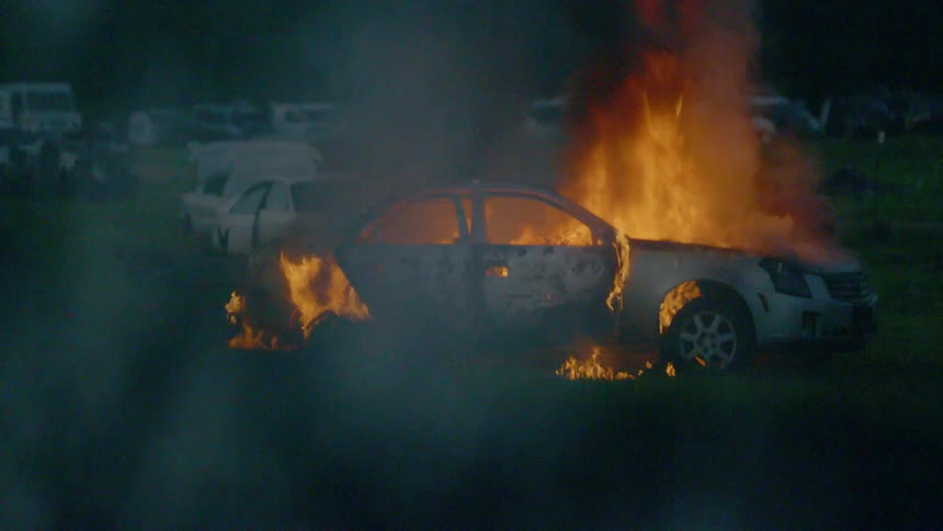 A car is in flames near other vehicles