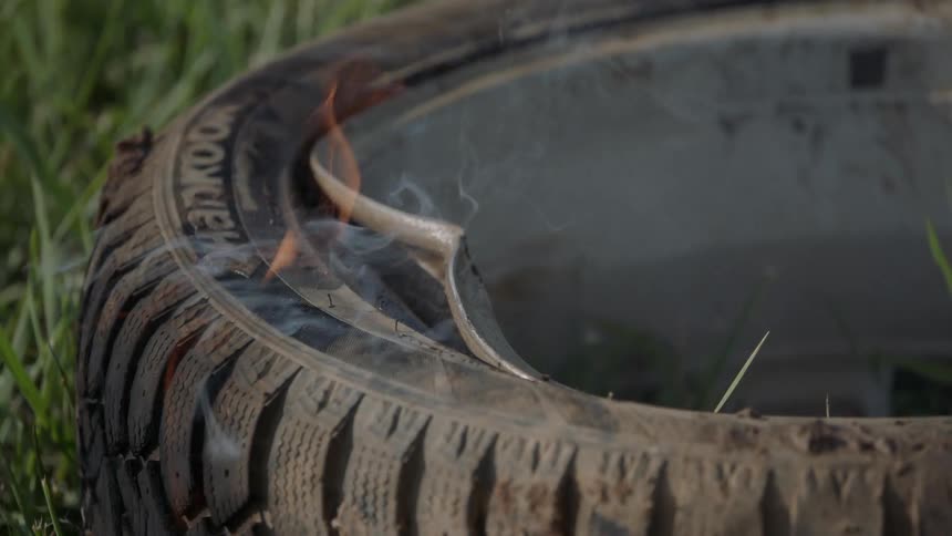A tire that is on fire in the middle of a field