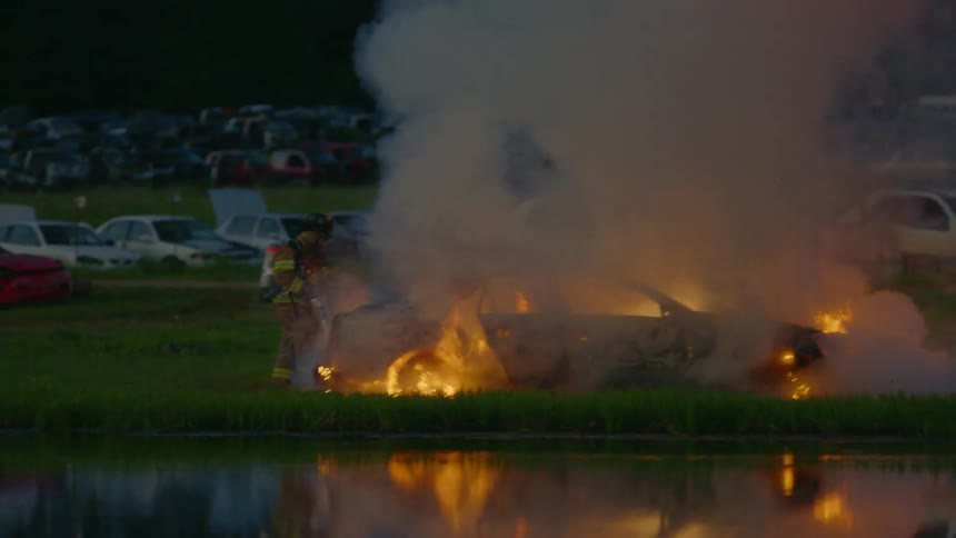 Firefighter extinguishes a car that is on fire